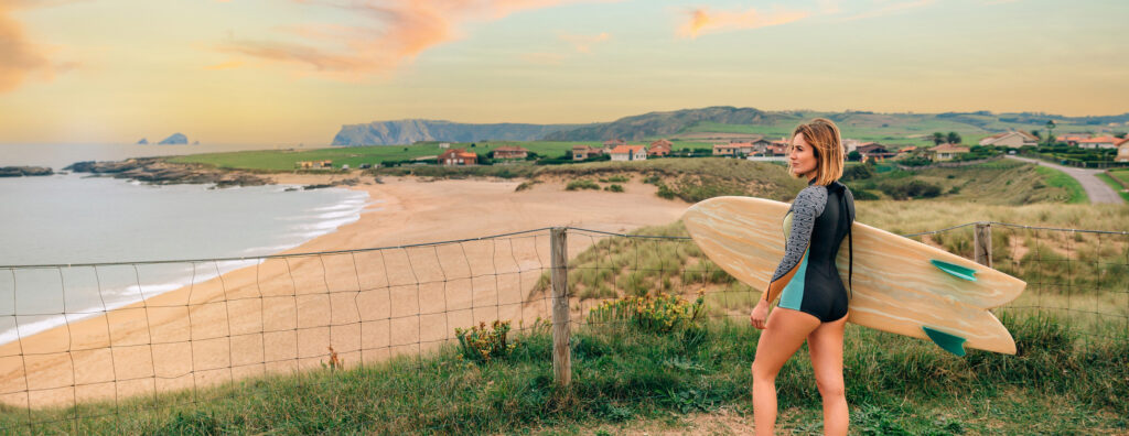 Woman with surfboard overlooking morning beach